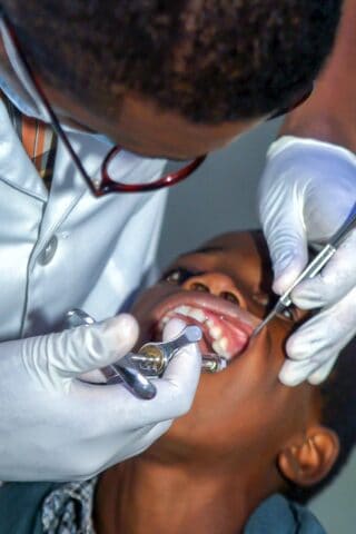 Black dentist treating black boy