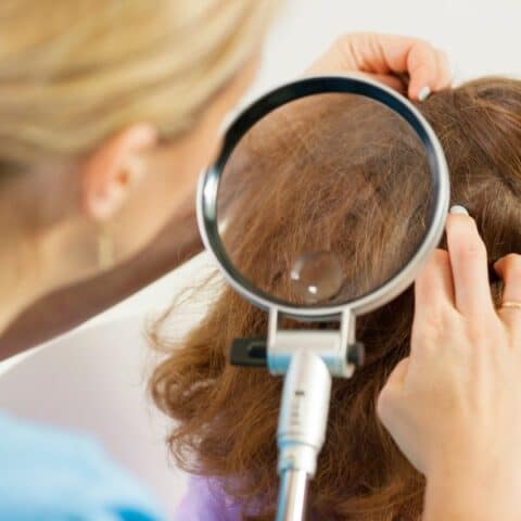 A woman examining hair using a magnifying glass