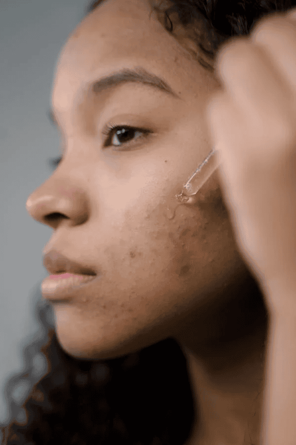 Black female applying oil to face