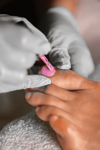 Gloved hands painting toenail