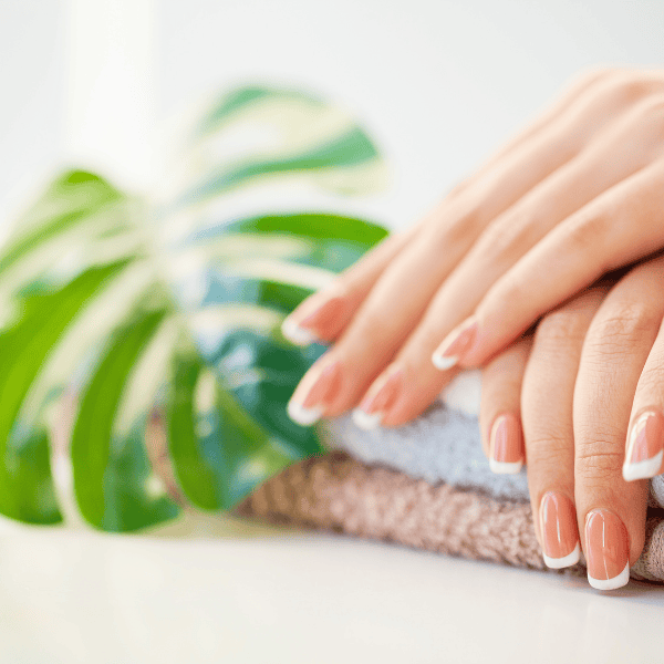 Manicured nails placed on a towel with a plant as a backdrop