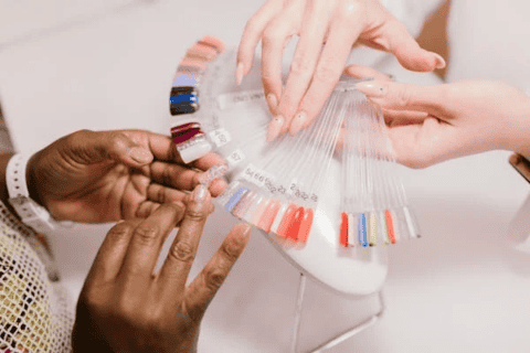 Hands holding acrylic nail samples of various colors