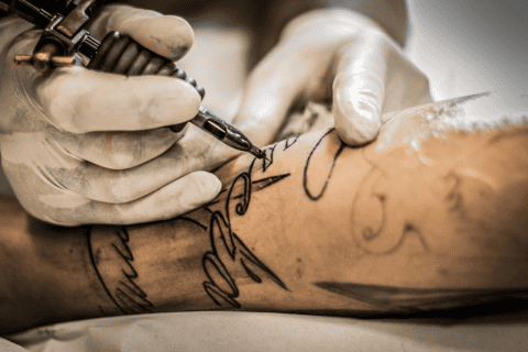 Hands tattooing arm