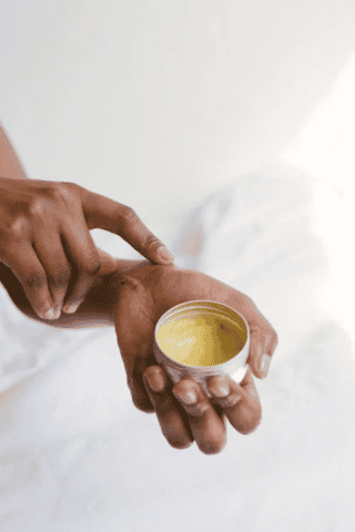 Individual applying salve to wrist against white background
