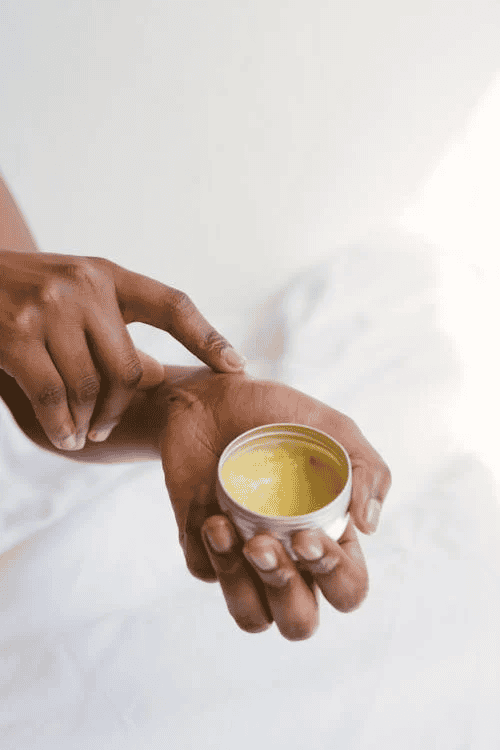 Individual applying salve to wrist against white background