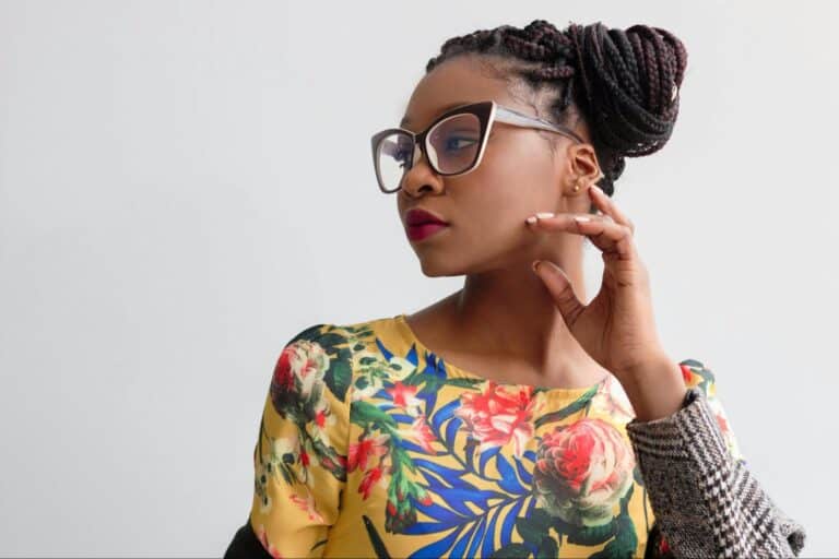 A woman wearing glasses is dressed in a yellow floral top.