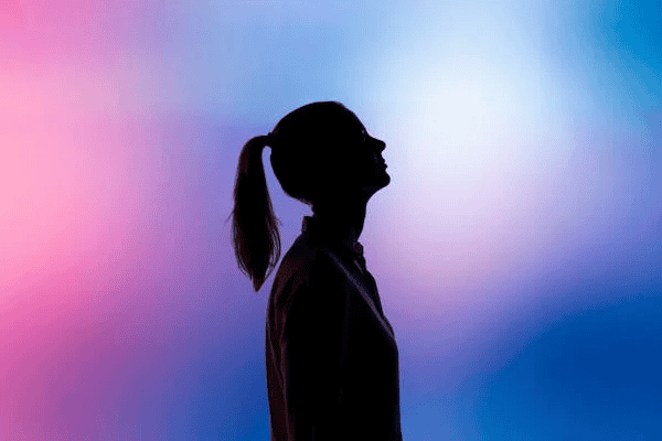 Silhouette of individual with ponytail against purple background